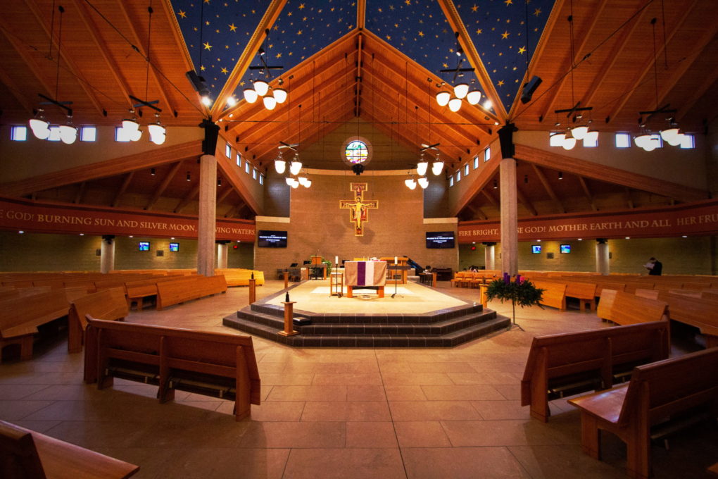 Interior of Saint Francis church with view of pews, altar, and blue starry ceiling.