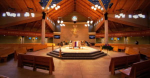 Interior of Saint Francis church with view of pews, altar, and blue starry ceiling.