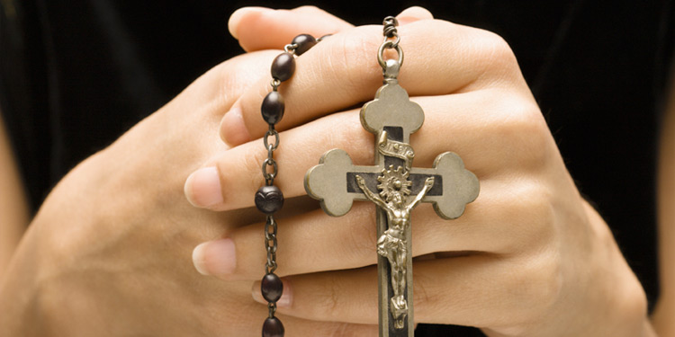 Hands holding a metal crucifix
