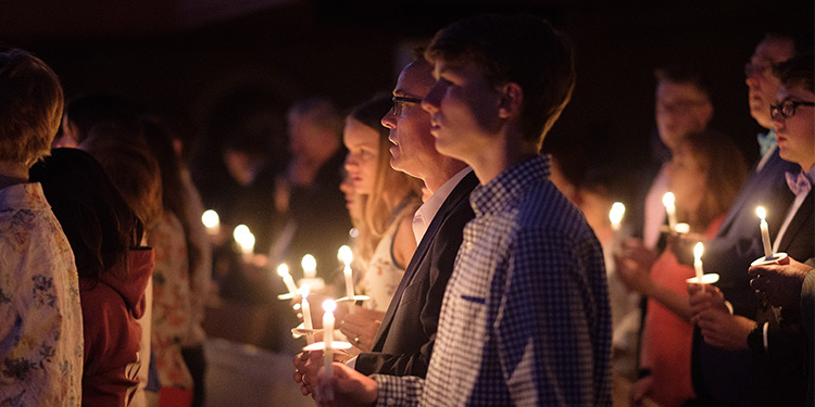 Church members hold lit candles during mass service